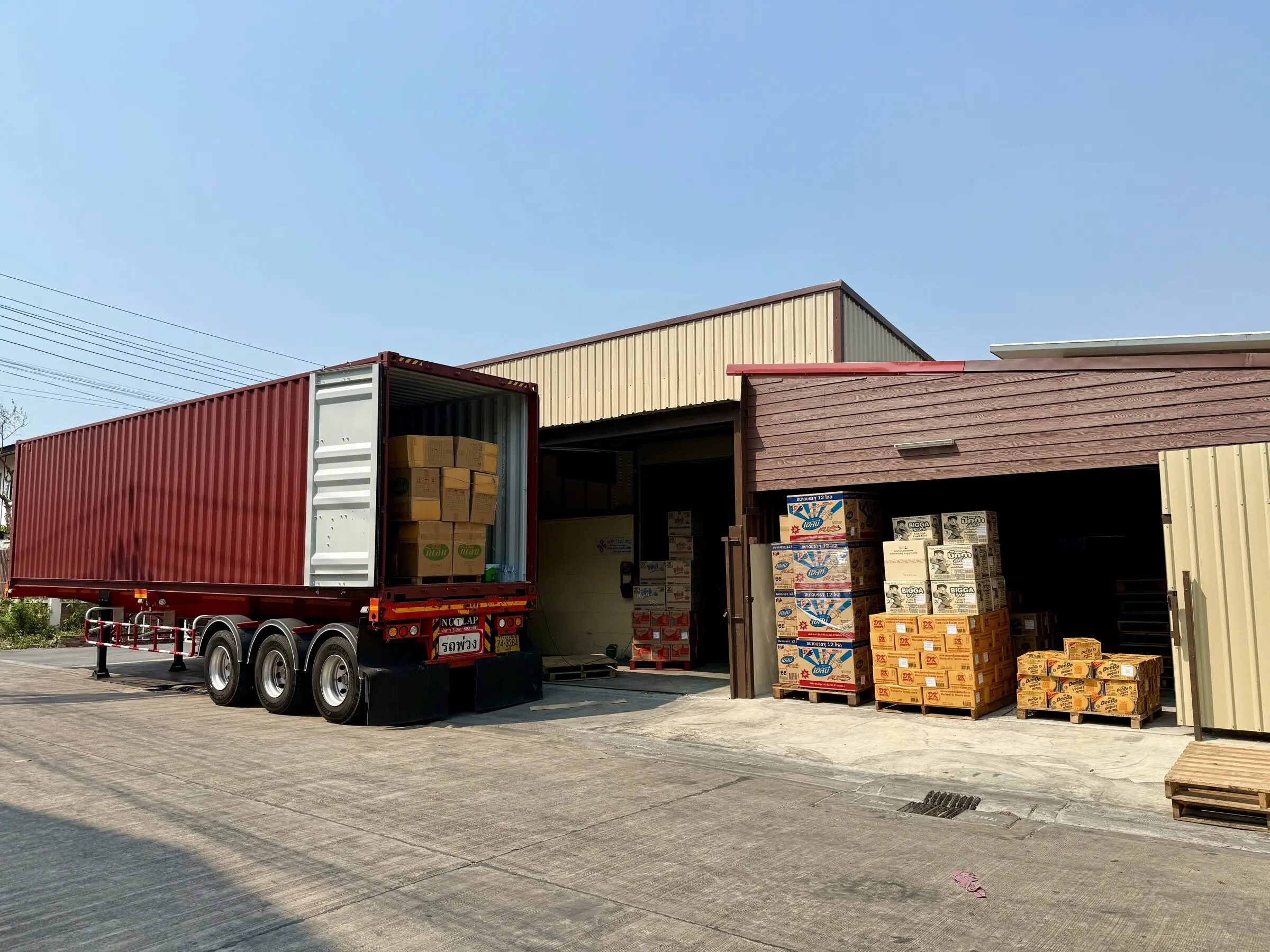 A 40-foot container backed up to aBit Trading's Bangkok warehouse, with palletised cartons of Thai consumer goods staged at the doors