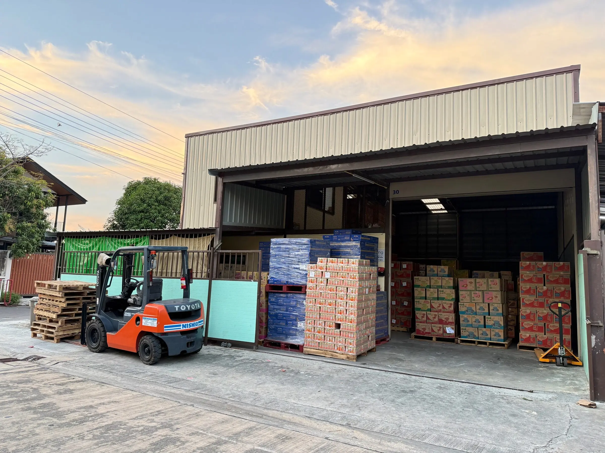 Palletised stock and a forklift at the warehouse doors in the evening after a day of loading