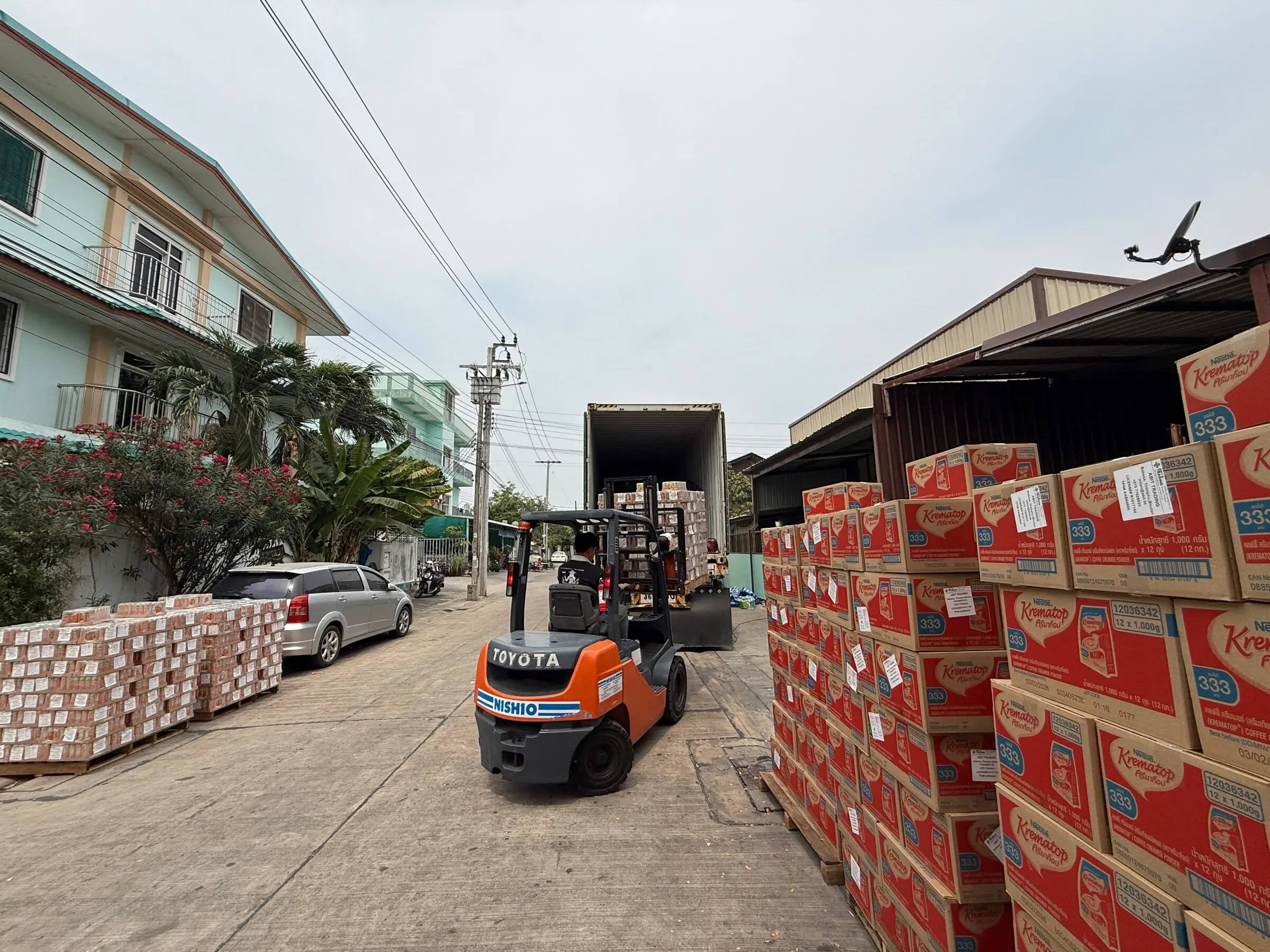 A forklift working between lanes of palletised cartons at the warehouse during container loading